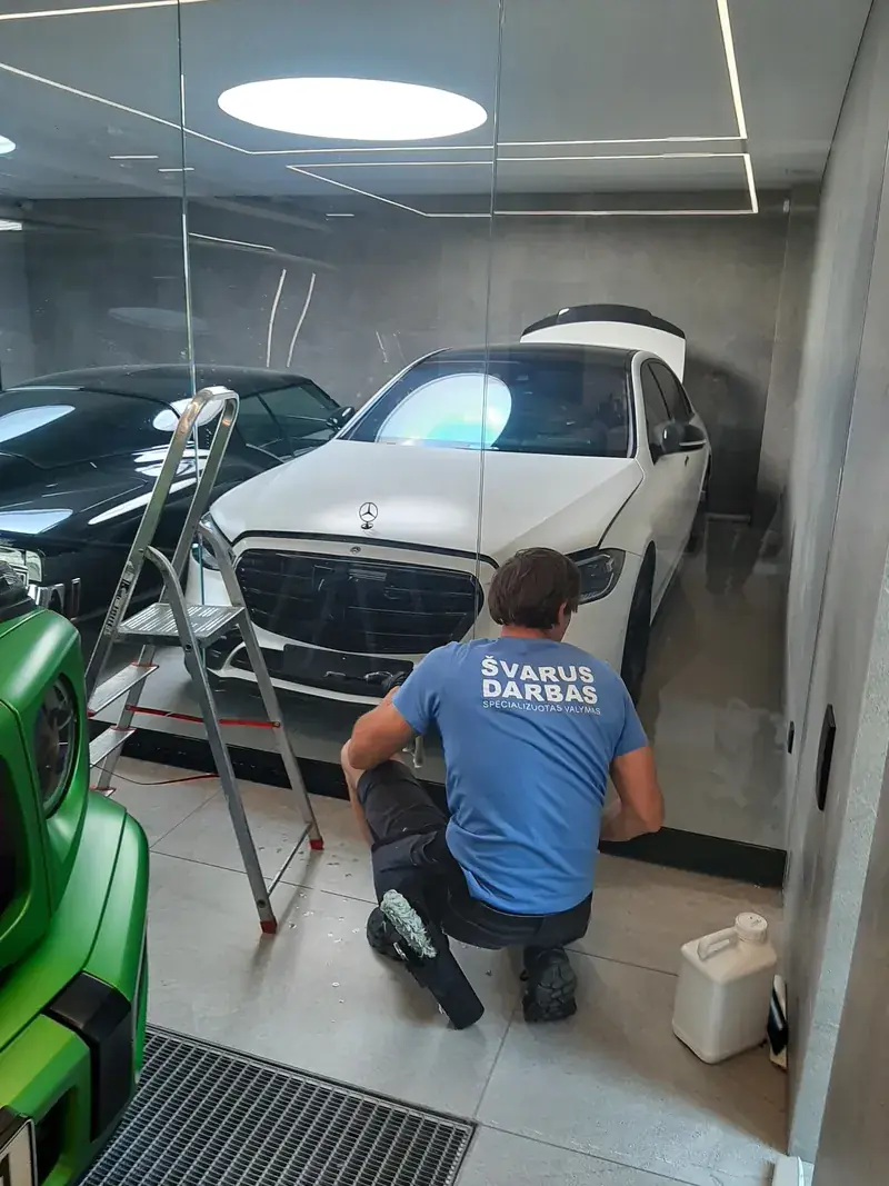 „Švarus darbas“ darbuotojas valo stiklinę automobilių salono pertvarą